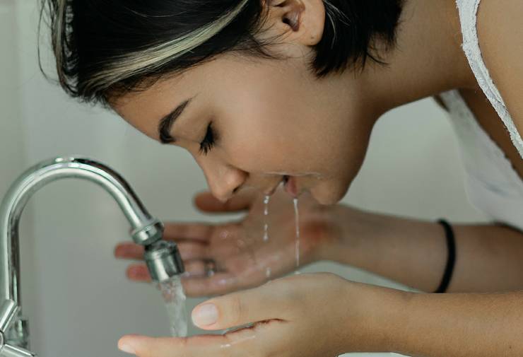 Una persona che beve acqua del rubinetto