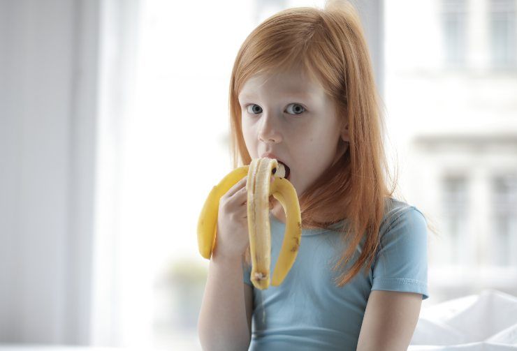 Una bambina che mangia la banana