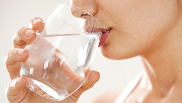 Giovane donna beve un bicchiere d'acqua