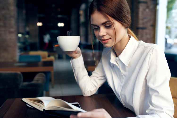 Donna che beve caffè e legge libro