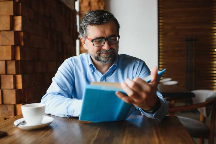 Uomo legge libro in caffè letterario