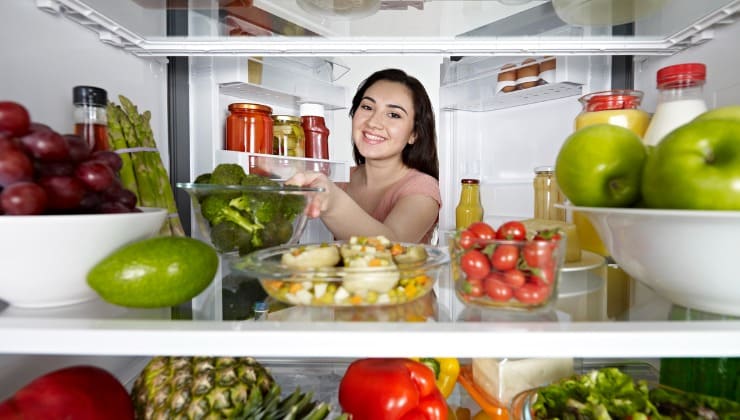 Donna mette cibo in frigorifero