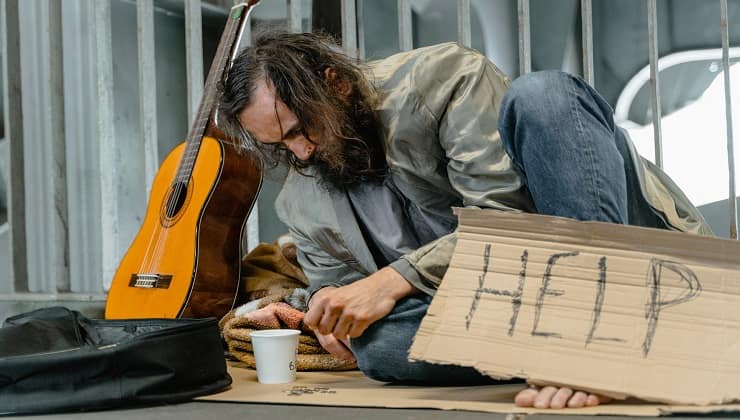 Uomo per strada con cartello chiede aiuto