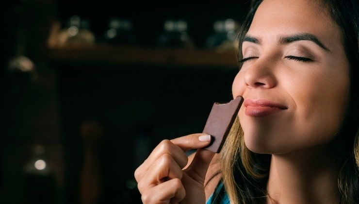 Donna mangia quadrato di cioccolata