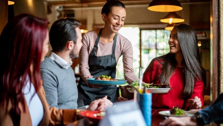 Cameriera serve cibo a un gruppo di clienti