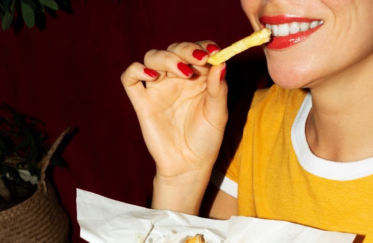 Una donna che mangia patatine fritte