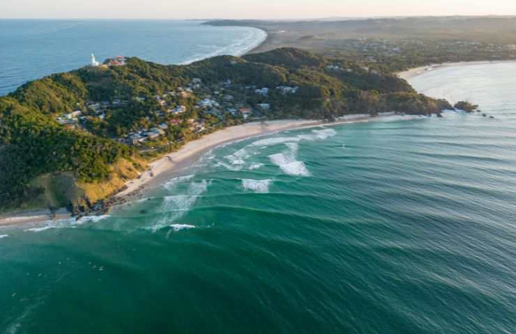 È considerata la città dei surfisti e degli hippie: andiamo alla scoperta di Byron Bay, paradiso dell'Australia. Byron Bay è un incantevole posto dell'Australia, animato da una vibrante vita culturale, portata avanti da musicisti di strada, artisti locali e da tanti negozi che mettono a disposizione cibo biologico, artigianato eco-friendly e ristoranti che propongono cucine multietniche e vegetariane. Scopriamo, dunque, insieme cosa fare e vedere a Byron Bay. Byron Bay, il posto dei surfisti e degli hippie in Australia A Byron Bay, c'è una atmosfera molto rilassata: non bisogna seguire regole. per quanto riguarda l'abbigliamento. Qui, infatti, si possono vedere persone camminare a piedi nudi, gruppi di amici che condividono birre ammirando le onde e viaggiatori da ogni angolo del mondo, pronti a sorridervi con un entusiasmo contagioso. Se state cercando un modo per staccare dalla vostra routine quotidiana, Byron Bay rappresenta il posto ideale per farlo, dopo aver percorso, ad esempio, la meravigliosa Pacific Road da Sidney a Brisbane. Cape Byron Waling Track e il faro di Byron Bay Partiamo con Cape Byron Walking Track, un percorso di oltre 4 chilometri che vi condurrà verso scogliere e foreste pluviali, con partenza e arrivo al centro di Byron Bay. C'è, poi, il faro di Cape Byron, simbolo iconico della città, da cui godere di una vista meraviglioso sull'oceano e sulle scogliere, dalle quali è possibile avvistare delfini, tartarughe e, se siete fortunati, anche balene in migrazione. Tale posto mette a disposizione infinite opportunità per gli amanti del mare, in quanto in questa zona si possono praticare diverse attività all'aperto, dal surf alle immersioni, fino poi al kayak tra delfini e tartarughe. Un paradiso per chi cerca l'adrenalina ma anche per chi desidera semplicemente ammirare l'alba sulla spiaggia. Nimbin, la capitale degli hippie Inoltre, potete passeggiare tra i mercati artigianali, come il Byron Bay Market o il Farmer’s Market, dove scoprire prodotti del posto e le opere d'arte, immergendosi, così, in un'atmosfera particolare che riflette, in sostanza, lo spirito libero della comunità di tale luogo.   Passiamo, poi, a Nimbin, la capitale hippie, una città eclettica, famosa per la sua cultura alternativa e le iniziative ambientali, nonché per essere un centro principale di eventi culturali che attirano visitatori da tutto il mondo. Escursioni al Nightcap National Park e alle Mynion Falls Non possono mancare escursioni al Night Cap National Park e alle Minion Falls, circondati da paesaggi naturali incontaminati e cascate superbe.  In questo angolo dell'Australia, inoltre, si può anche effettuare un ritiro spirituale, dove dedicarsi a momenti intimi, praticando yoga, meditazione e trattamenti benessere, che si fondono anche alle tradizioni aborigene.